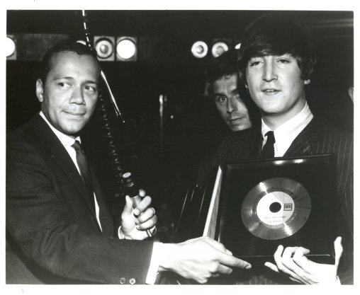 Randall Wood presents John Lennon with a gold record
for  Twist and Shout'. In rear is Beatle publicist Derek Taylor. 